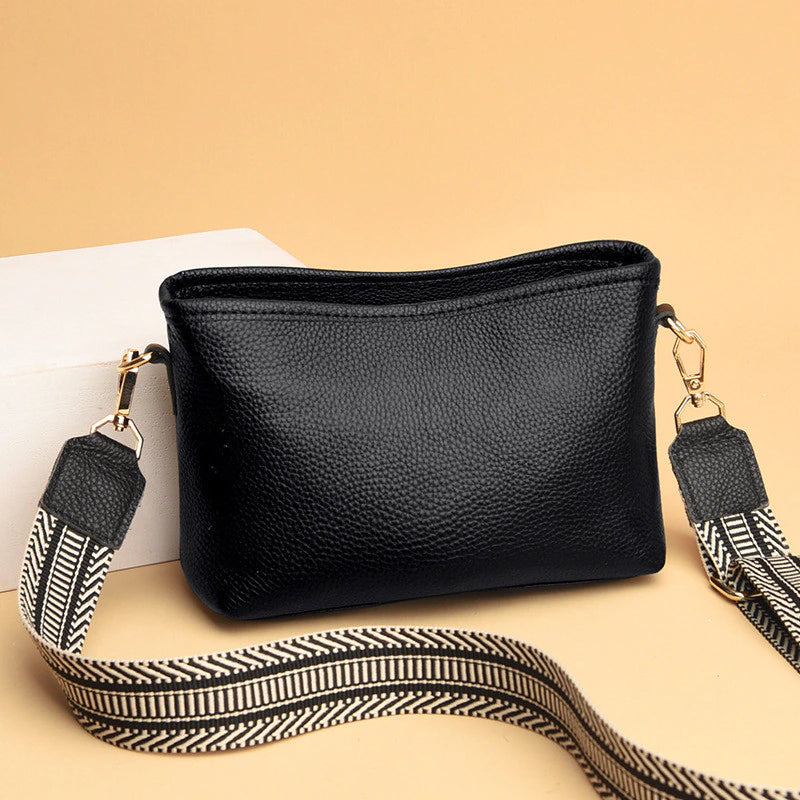 Schwarze Lederhandtasche mit abnehmbarem, gemustertem Schultergurt. Stilvoll und vielseitig, ideal für Alltag und besondere Anlässe.