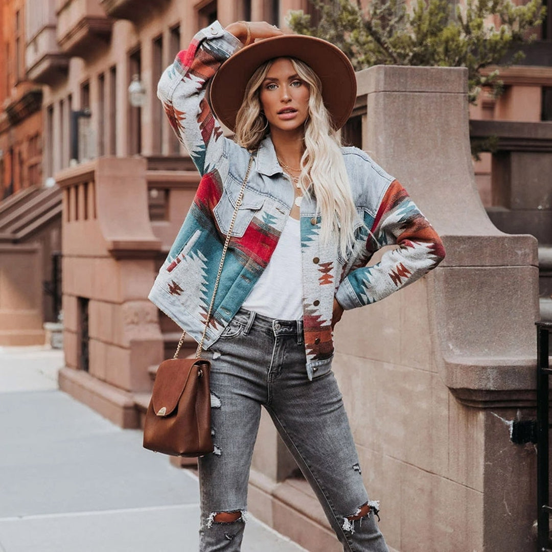 Stylische Frau in bunter Azteken-Jacke, grauen Jeans und Hut posiert urban. Modetrend, Streetstyle, Herbstmode, Damenbekleidung, Accessoires.