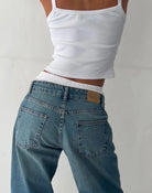 Frau in blauer Vintage-Jeans und weißem Top, modisch, lässig, Rückansicht.