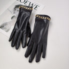 Schwarze Lederhandschuhe mit goldener Kette, elegant und stilvoll, auf einem Magazin liegend. Perfekt für Modeaccessoires und Luxus-Styling.