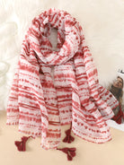 Roter und weißer gestreifter Schal mit Quasten, ideal für Damenmode. Perfekt als Accessoire für Herbst und Winter. Hochwertiger Stoff.
