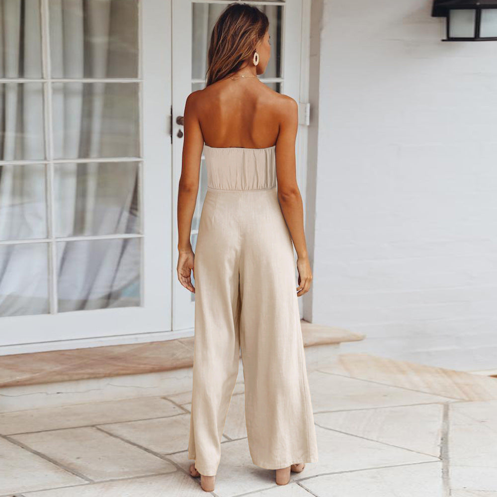 Frau in eleganter, beigefarbener Jumpsuit-Mode vor Glastür. Sommeroutfit, stilvoll, modern, Damenbekleidung, trendige Mode.