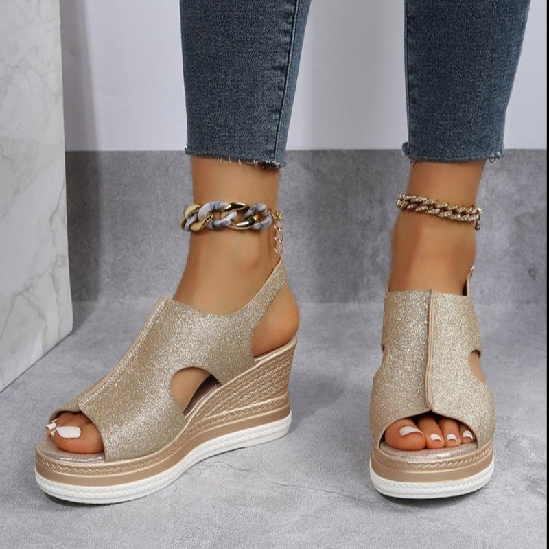 Goldene Keilsandaletten mit Glitzer, offener Zehenpartie und Plateauabsatz. Perfekt für Sommermode und elegante Anlässe. Damenmode, Schuhe.