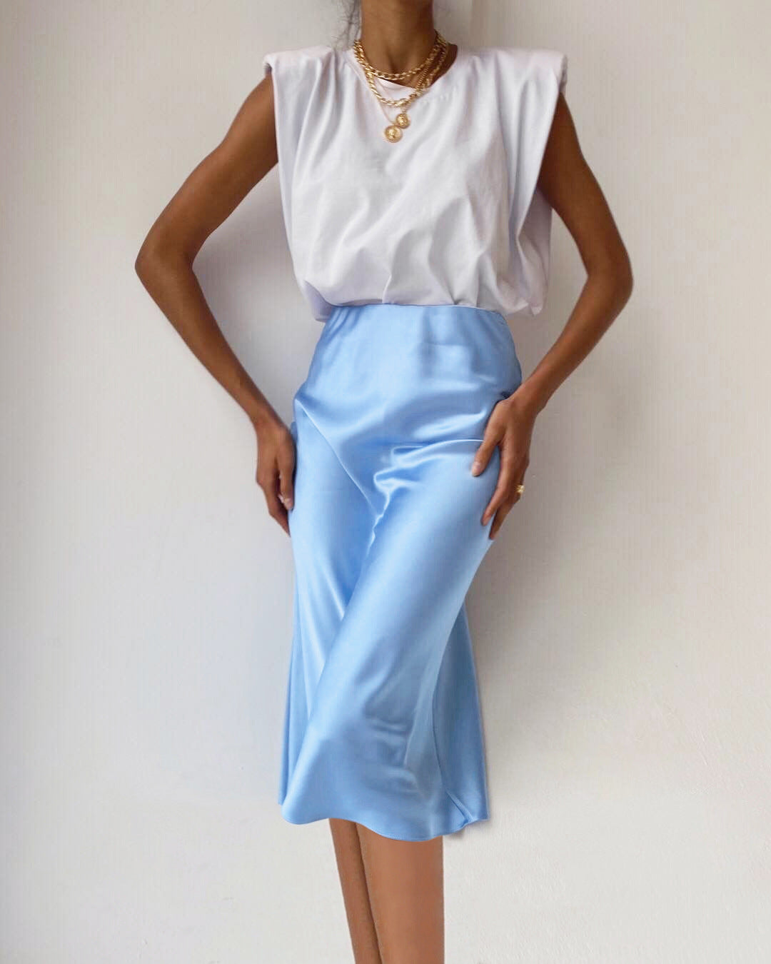 Elegantes Outfit mit weißem ärmellosen Oberteil und hellblauem Satinrock. Perfekt für Sommermode, Damenbekleidung, stilvolle Freizeitkleidung.