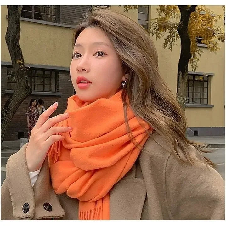 Frau mit orangefarbenem Schal und braunem Mantel im Herbst. Modetrend, Herbstmode, stilvolle Kleidung, Outdoor-Fotografie, Streetstyle.
