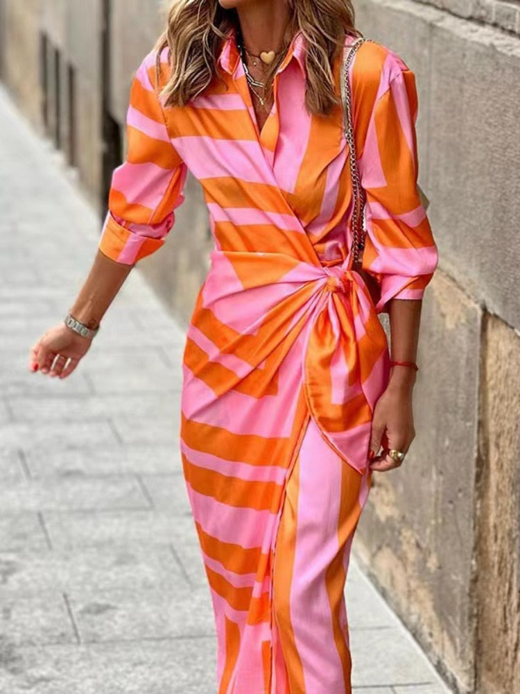 Frau in einem eleganten, gestreiften Wickelkleid in Pink und Orange, ideal für Sommermode. Perfekt für stilvolle, trendige Outfits.