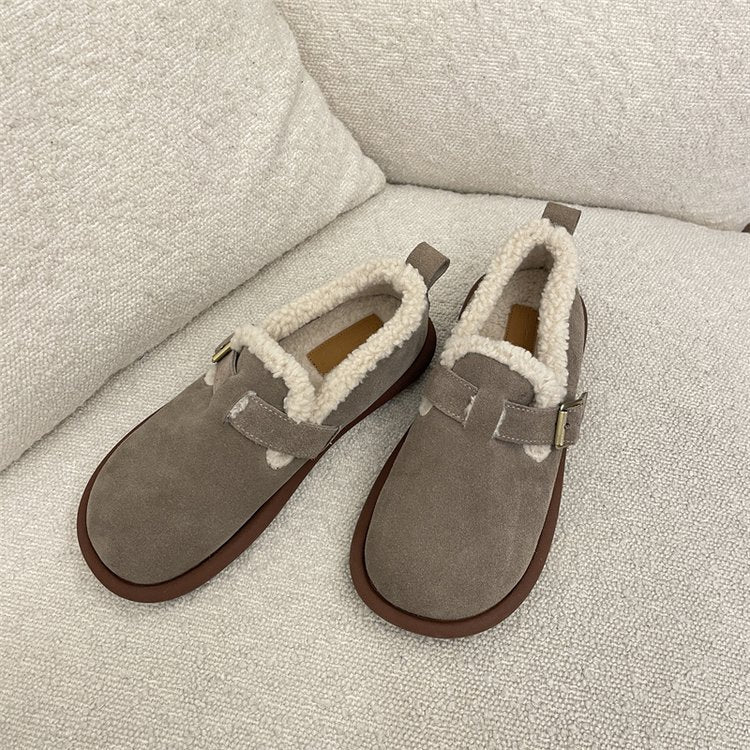 Beige Hausschuhe mit weichem Futter auf einem Sofa. Perfekt für Komfort und Wärme. Ideal für gemütliche Winterabende zu Hause.