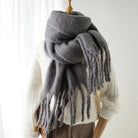 Grauer Wollschal mit Fransen, kuschelig und warm, ideal für Herbst und Winter. Perfektes Accessoire für stilvolle Damenmode.