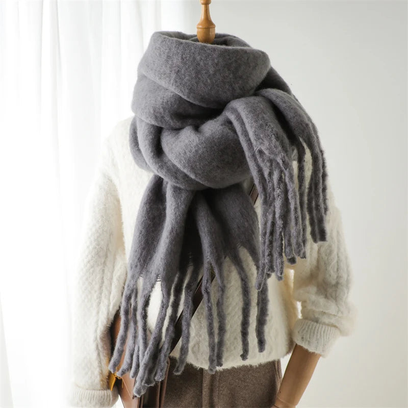 Grauer Wollschal mit Fransen, kuschelig und warm, ideal für Herbst und Winter. Perfektes Accessoire für stilvolle Damenmode.