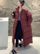 Frau in langem, rotem Daunenmantel, kombiniert mit schwarzer Leggings und flauschigen Hausschuhen. Wintermode, Damenbekleidung, stilvoll.