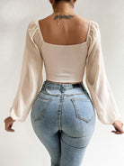 Damenmode: Elegante, langärmelige Bluse mit quadratischem Ausschnitt, kombiniert mit hoch taillierten Jeans. Perfekt für stilvolle Freizeitlooks.