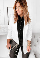 Frau in elegantem weißen Blazer, schwarzer Bluse und Lederhose. Modetrends, Damenmode, stilvolle Outfits, Business-Look, Modeaccessoires.