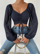 Damenmode: Schwarzes, langärmliges Crop-Top mit Raffung, kombiniert mit blauen Jeans. Trendige, elegante Kleidung für stilvolle Outfits.