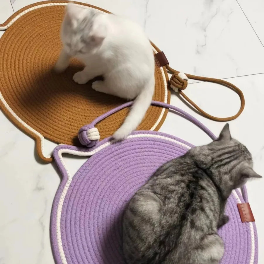 Zwei Katzen auf runden, geflochtenen Katzenmatten in Braun und Lila auf weißem Boden.