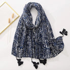 Dunkelblauer Schal mit weißem, geometrischem Muster und schwarzen Quasten. Perfekt für modische Akzente im Herbst und Winter.