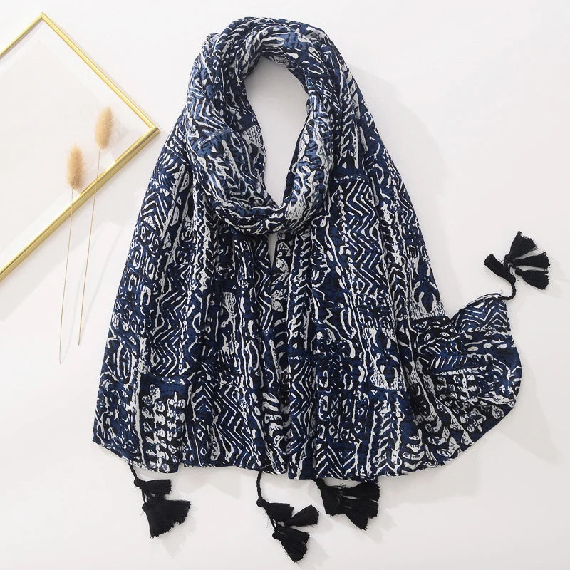 Dunkelblauer Schal mit weißem, geometrischem Muster und schwarzen Quasten. Perfekt für modische Akzente im Herbst und Winter.