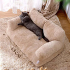 Graues Kätzchen auf beigem, plüschigem Katzenbett, 65 cm, auf Teppich im Wohnzimmer.
