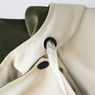 Beige Regenjacke mit Kapuze, schwarzem Kordelzug und Knopfdetail. Wasserdicht, modisch, ideal für Outdoor-Aktivitäten. Hochwertige Verarbeitung.