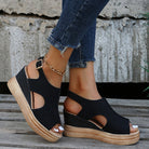 Schwarze Keilsandalen mit offenem Zeh und Knöchelriemen, kombiniert mit blauen Jeans. Perfekt für Sommermode und lässige Outfits.