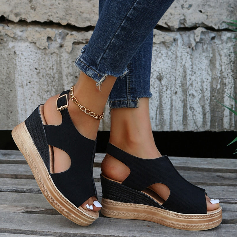 Schwarze Keilsandalen mit offenem Zeh und Knöchelriemen, kombiniert mit blauen Jeans. Perfekt für Sommermode und lässige Outfits.