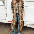 Damenmode: Langer Strickmantel mit Kunstfellkragen, Boho-Stil, ideal für Herbst, kombiniert mit Jeans und Gürtel, lässig und stilvoll.