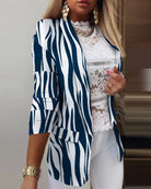 Eleganter Damenblazer mit blau-weißem Zebramuster, kombiniert mit weißer Spitzenbluse und goldenen Accessoires. Perfekt für modische Outfits.
