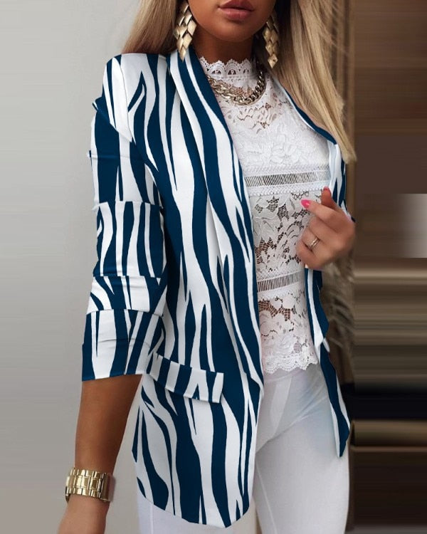 Eleganter Damenblazer mit blau-weißem Zebramuster, kombiniert mit weißer Spitzenbluse und goldenen Accessoires. Perfekt für modische Outfits.