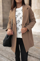 Damenmode: Eleganter beiger Mantel, kombiniert mit weißem "Paris" Pullover und schwarzer Tasche. Perfekt für stilvolle Herbst-Looks.