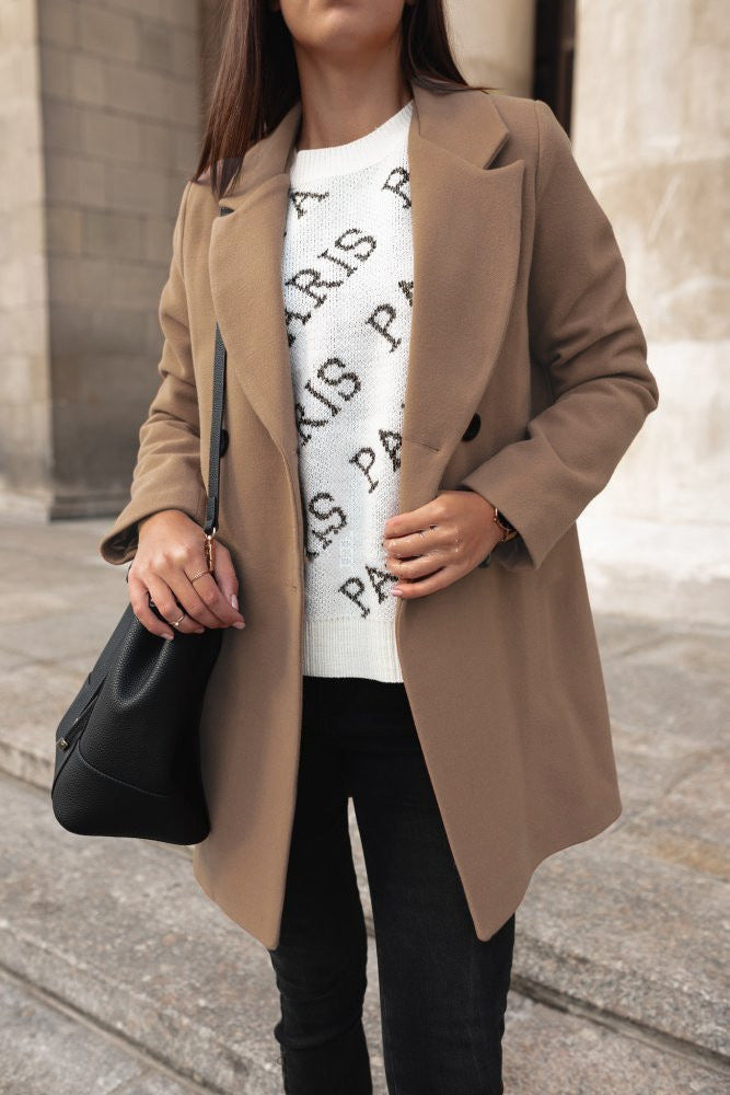 Damenmode: Eleganter beiger Mantel, kombiniert mit weißem "Paris" Pullover und schwarzer Tasche. Perfekt für stilvolle Herbst-Looks.
