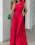 Elegantes rotes Abendkleid mit asymmetrischem Schnitt und Blumenapplikation, ideal für festliche Anlässe. Perfekt kombiniert mit grüner Clutch.
