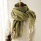 Großer, grüner Wollschal auf weißem Pullover, ideal für Wintermode. Weicher, warmer Schal mit Fransen, perfekt für kalte Tage und stilvolle Outfits.