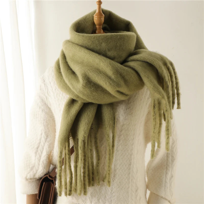 Großer, grüner Wollschal auf weißem Pullover, ideal für Wintermode. Weicher, warmer Schal mit Fransen, perfekt für kalte Tage und stilvolle Outfits.