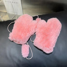Rosa Plüsch-Fäustlinge auf schwarzem Hintergrund, ideal für Wintermode. Flauschige Handschuhe, warm und stilvoll, perfekt für kalte Tage.