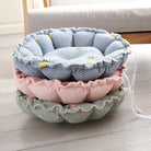 Drei runde, weiche Haustierbetten in Blau, Rosa und Grün auf Holzboden, ideal für Katzen und kleine Hunde.