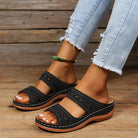 Damen Sandalen, schwarz, mit Lochmuster und Keilabsatz, kombiniert mit zerrissenen Jeans. Bequem, modisch, ideal für Sommeroutfits.