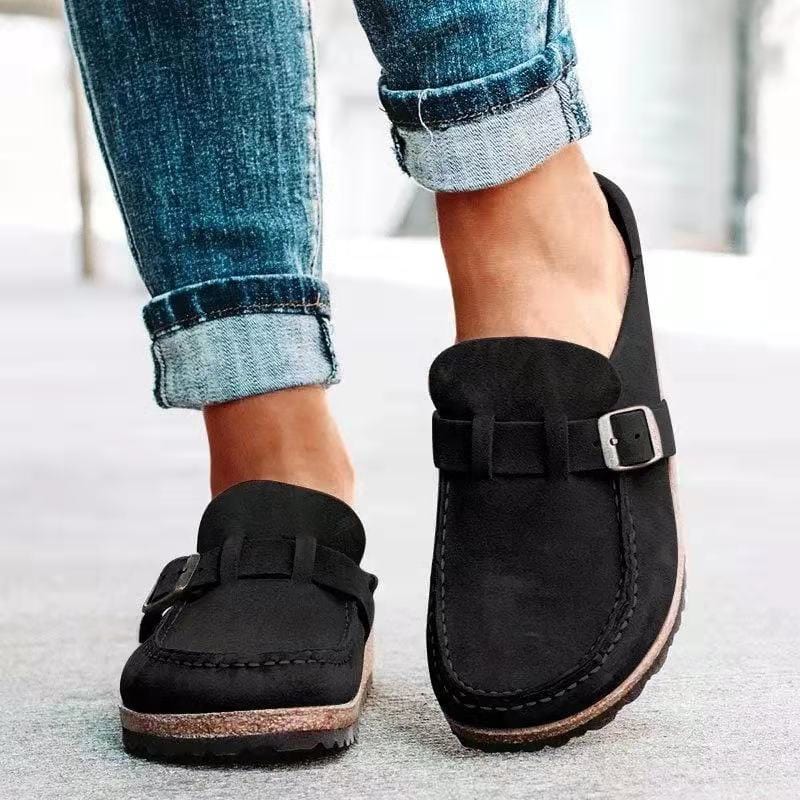 Schwarze Mokassins mit Schnalle, kombiniert mit hochgekrempelten Jeans. Bequeme, stilvolle Schuhe für Freizeit und Alltag.