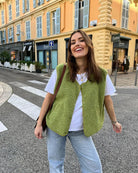 Junge Frau in grüner Weste und weißem T-Shirt auf Stadtstraße. Modetrend, lässiger Look, urbaner Stil, Streetwear, Modefotografie.