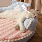 Schlafende Katze auf rosa-blauem Plüschbett, gemütlich, Haustierbett, Katzenbett, weich.