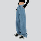 Weite, gestreifte Jeans für Damen, kombiniert mit schwarzen Sneakern und einem schwarzen Langarmshirt. Trendige Mode, lässiger Streetwear-Stil.