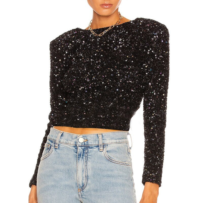 Schwarzes Pailletten-Oberteil mit langen Ärmeln, kombiniert mit hellblauen Jeans. Perfekt für glamouröse Abendmode und Partys.
