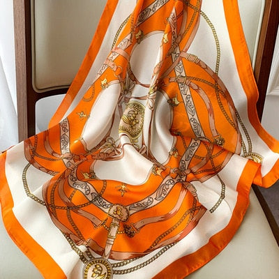 Luxuriöses Seidentuch mit orangefarbenem Kettendesign, ideal als modisches Accessoire. Perfekt für stilvolle Outfits und elegante Anlässe.