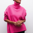 Damenpullover in leuchtendem Pink mit Rollkragen, aus weichem Strickmaterial. Modischer Oversize-Look, ideal für Herbst und Winter.
