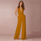 Frau in elegantem, senfgelbem Jumpsuit mit tiefem V-Ausschnitt und weitem Bein. Perfekt für stilvolle Anlässe. Damenmode, trendige Jumpsuits.