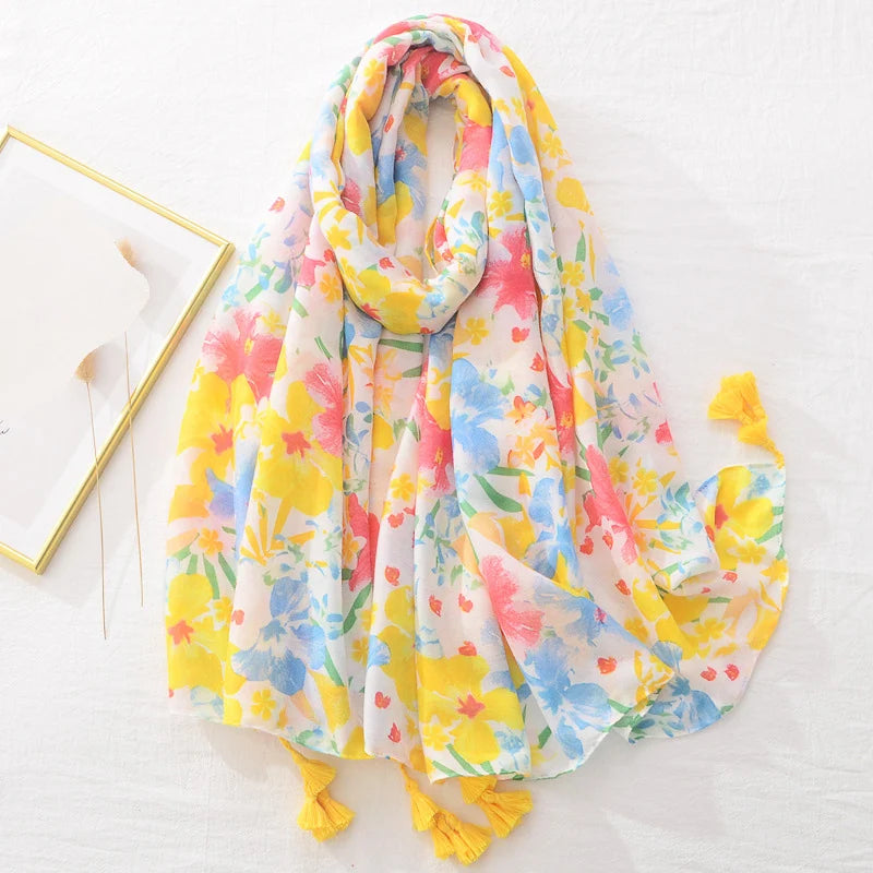 Bunter Blumenschal aus leichtem Stoff mit gelben Quasten, ideal für Frühling und Sommer. Perfektes Accessoire für modische Outfits.