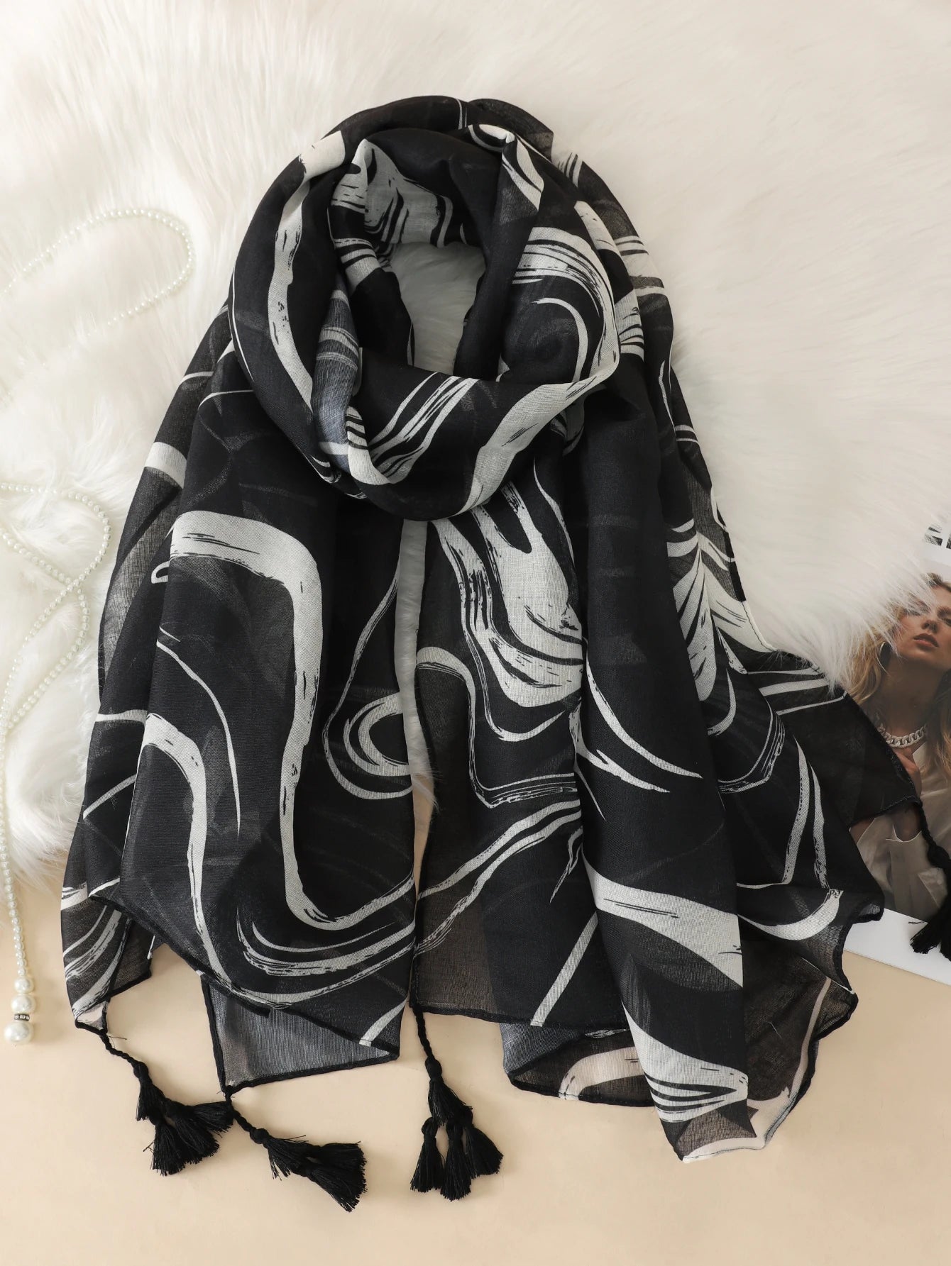 Eleganter schwarzer Schal mit weißem abstraktem Muster und Quasten, ideal für Damenmode, Accessoires, Herbst- und Winteroutfits.