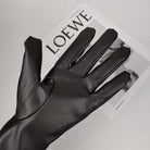Schwarzer Lederhandschuh auf LOEWE-Magazin, stilvolles Accessoire, hochwertiges Material, Mode, Eleganz, zeitloses Design, Luxus.