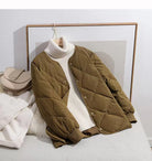 Damen Steppjacke in Khaki mit Druckknöpfen, kombiniert mit weißem Rollkragenpullover. Modische Herbst-Winter-Kleidung, warm und stilvoll.