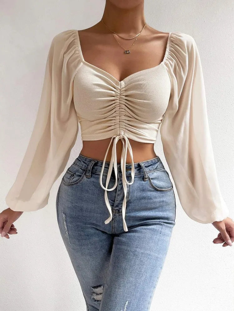 Damen-Crop-Top mit langen Ärmeln und Raffung, kombiniert mit modischen Jeans. Perfekt für trendige Outfits und stilvolle Freizeitlooks.
