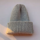 Graue Strickmütze aus weichem, geripptem Material, ideal für Wintermode. Perfekt für Damen und Herren, warm und stilvoll.