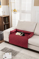 Hund auf rotem, gestepptem Sofaschutz, beige Couch, Wohnzimmer, modernes Design.